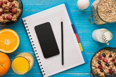 Mavi ahşap arka plan, üstten görünüm kaşık süt ve meyve bir kase ile yulaf gevreği