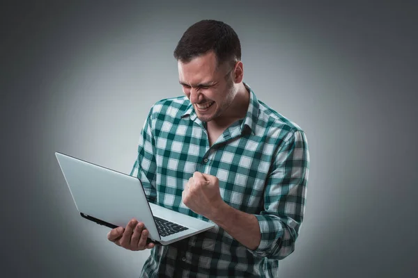 Atractivo modelo de hombre de negocios en camisa verde aislado en gris trabajando con el ordenador portátil, mostrando algo a mano izquierda . —  Fotos de Stock