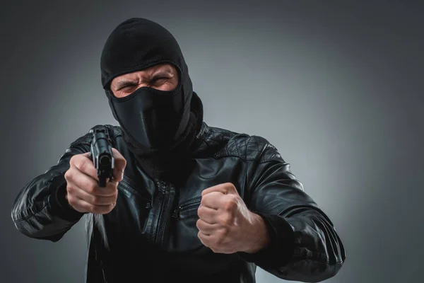 Burglar or terrorist in black mask shooting with gun.