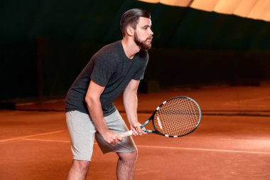 Yakışıklı delikanlı t-shirt holding Tenis raket tenis kortunda