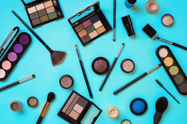 Çeşitli kozmetik ve mavi arka plan üzerinde fırçalar