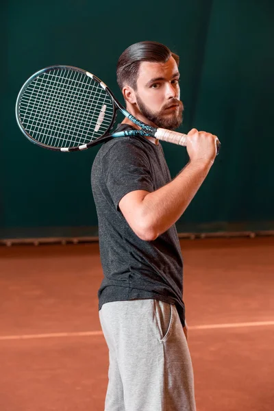 Beau jeune homme en t-shirt avec raquette sur court de tennis — Photo