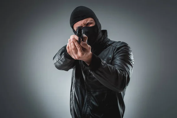 Inbrottstjuv eller terrorism i svart mask skjuta med pistol. — Stockfoto