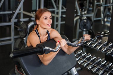 Spor salonundaki simülatörde egzersiz yapan kaslı genç kadın.