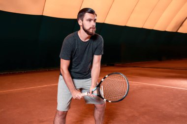 Yakışıklı delikanlı t-shirt holding Tenis raket tenis kortunda