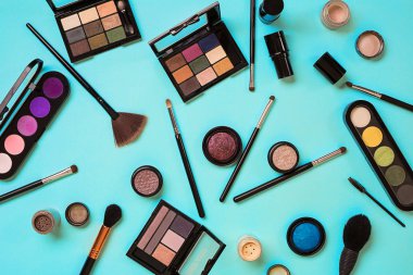 Çeşitli kozmetik ve mavi arka plan üzerinde fırçalar