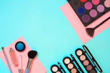 Çeşitli kozmetik ve mavi arka plan üzerinde fırçalar