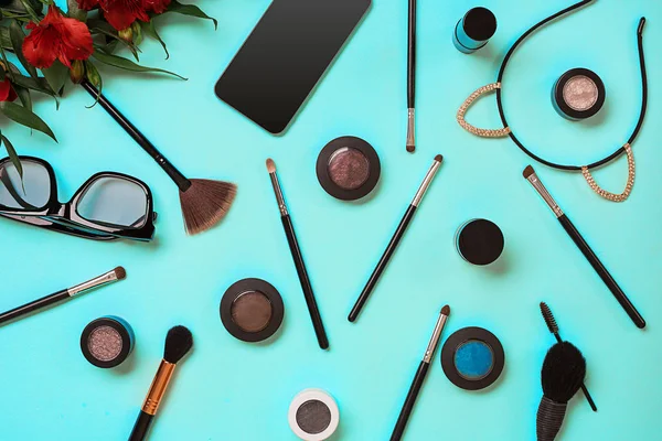 Verschiedene Kosmetika und Pinsel auf blauem Hintergrund — Stockfoto