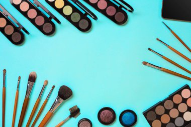 Çeşitli kozmetik ve mavi arka plan üzerinde fırçalar