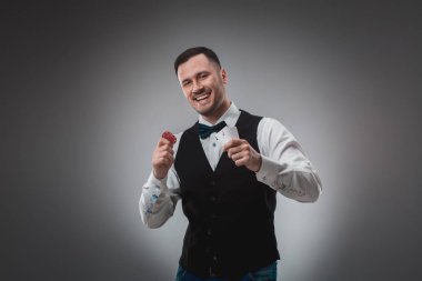 Gömlek ve yelek genç adam onun kartlarını gösterir ve poker fişleri elinde stüdyo çekim tutar