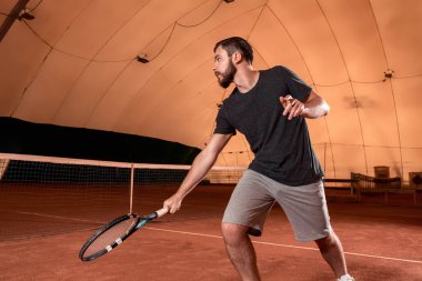 Yakışıklı delikanlı t-shirt holding Tenis raket tenis kortunda