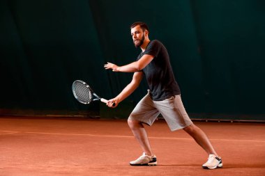 Yakışıklı delikanlı t-shirt holding Tenis raket tenis kortunda