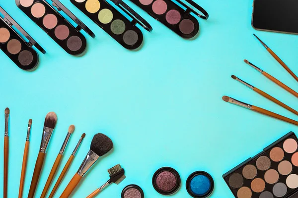 Çeşitli kozmetik ve mavi arka plan üzerinde fırçalar