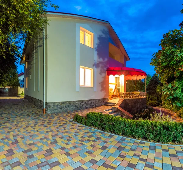 Horizontale Ansicht des Einfamilienhauses mit Patio. Abends. Gelbes Licht aus Fenstern — Stockfoto