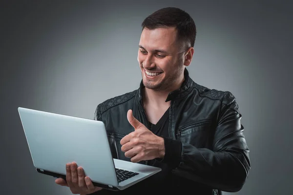Portret młodego człowieka przystojny za pomocą laptopa, na sobie czarną skórzaną kurtkę. — Zdjęcie stockowe