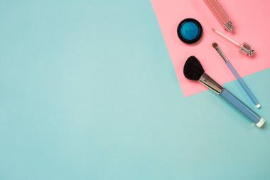 Renkli kozmetik mavi çalışma alanı ile kopya alanı üzerinde. Kozmetik yapmak sanatçı nesneleri: ruj, göz gölgeler, toz, makyaj için araçlar. Üstten Görünüm.