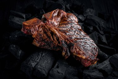 Grilling a tasty tender marinated t-bone steak on a coals. clipart