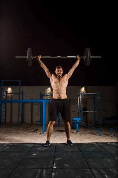 Man makes exercises with barbell — Stock Photo, Image