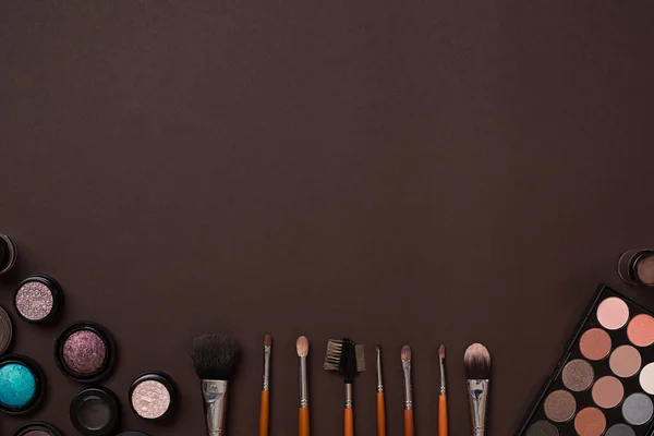 Varios cosméticos y pinceles sobre fondo marrón — Foto de Stock