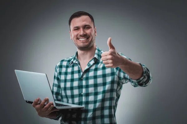 Atrakcyjny biznes człowiek modelu w zielonej koszuli na białym tle na szary pracę z laptopem, Wyświetlono coś przez lewą ręką. — Zdjęcie stockowe