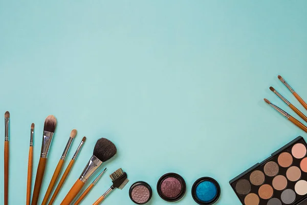 Cosméticos coloridos en el lugar de trabajo azul con espacio de copia. Cosméticos conforman objetos de artista: sombras de ojos, herramientas para el maquillaje. . — Foto de Stock