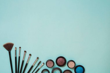 Renkli kozmetik mavi çalışma alanı ile kopya alanı üzerinde. Kozmetik yapmak sanatçı nesneleri: göz gölgeler, makyaj için araçlar. Üstten Görünüm.