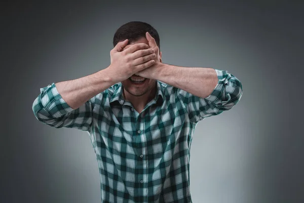 Mann bedeckt seine Augen mit Hand, legerer Kleidung. Studioaufnahme. — Stockfoto