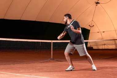 Yakışıklı delikanlı t-shirt holding Tenis raket tenis kortunda