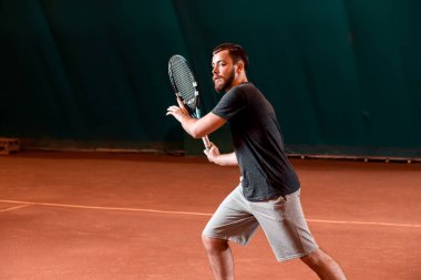 Yakışıklı delikanlı t-shirt holding Tenis raket tenis kortunda