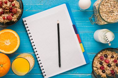 Mavi ahşap arka plan, üstten görünüm kaşık süt ve meyve bir kase ile yulaf gevreği