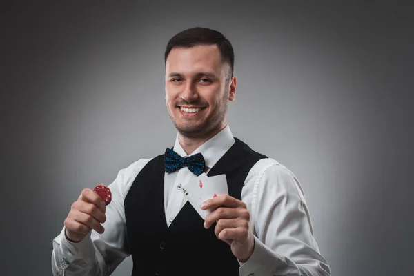 Νεαρός άνδρας στο πουκάμισο και γιλέκο δείχνει τα χαρτιά του και να κατέχει μάρκες πόκερ στα χέρια του, πυροβόλησε στούντιο — Φωτογραφία Αρχείου