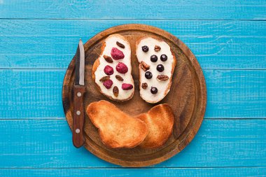 Tereyağı sandviç sağlıklı kepekli ekmek üzerinde taze ahududu, kuş üzümü ve kuru üzüm ile tepesinde. Üstten Görünüm