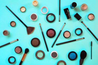 Çeşitli kozmetik ve mavi arka plan üzerinde fırçalar