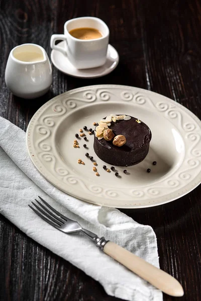 Schön dekorierter Schokoladenkuchen mit goldenen Nüssen und einer Tasse Kaffee — Stockfoto