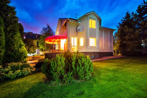 Horizontale Ansicht des Einfamilienhauses mit Patio. Abends. Gelbes Licht aus Fenstern — Stockfoto