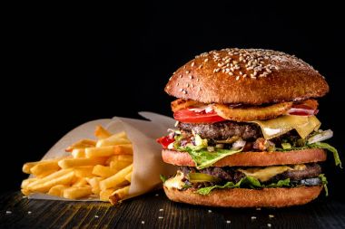 Zanaat sığır eti hamburger ve patates kızartması siyah arka plan üzerine izole ahşap tablo.