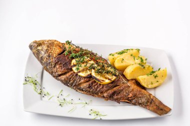 레몬, 로즈마리 감자와 구운된 잉어 물고기를 닫습니다.