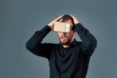 Gri arka plan üzerinde yeni bir sanal gerçeklik kulaklık kullanan adam