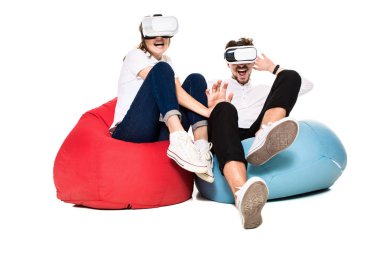 Sanal gerçeklik beyaz arka plan üzerinde izole beanbags üzerinde oturmuş yaşandığı heyecanlı genç Çift