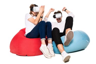 Sanal gerçeklik beyaz arka plan üzerinde izole beanbags üzerinde oturmuş yaşandığı heyecanlı genç Çift