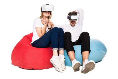 Sanal gerçeklik beyaz arka plan üzerinde izole beanbags üzerinde oturmuş yaşandığı heyecanlı genç Çift
