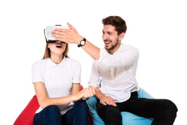 Sanal gerçeklik beyaz arka plan üzerinde izole beanbags üzerinde oturmuş yaşandığı heyecanlı genç Çift