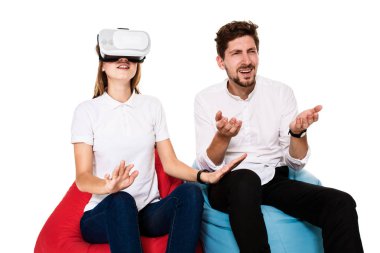 Sanal gerçeklik beyaz arka plan üzerinde izole beanbags üzerinde oturmuş yaşandığı heyecanlı genç Çift