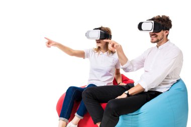Sanal gerçeklik beyaz arka plan üzerinde izole beanbags üzerinde oturmuş yaşandığı heyecanlı genç Çift