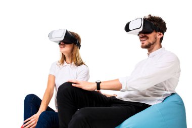 Sanal gerçeklik beyaz arka plan üzerinde izole beanbags üzerinde oturmuş yaşandığı heyecanlı genç Çift