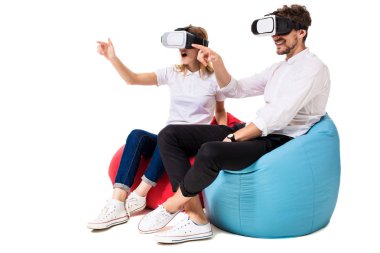 Sanal gerçeklik beyaz arka plan üzerinde izole beanbags üzerinde oturmuş yaşandığı heyecanlı genç Çift