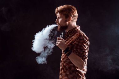 Genç adam elektronik sigara içiyor.