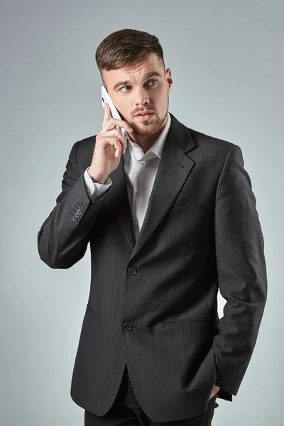 Retrato de un hombre de negocios guapo haciendo una llamada telefónica contra fondo gris —  Fotos de Stock