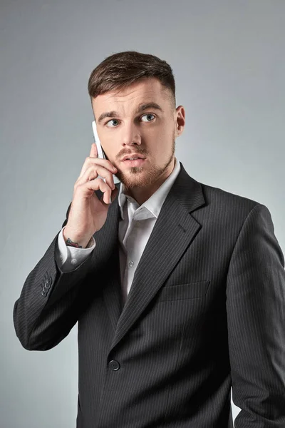 Retrato de un hombre de negocios guapo haciendo una llamada telefónica contra fondo gris —  Fotos de Stock