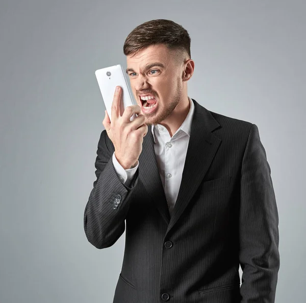 Retrato de un hombre de negocios guapo haciendo una llamada telefónica contra fondo gris —  Fotos de Stock